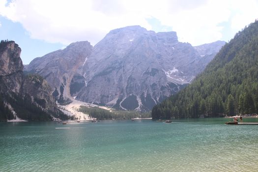 Braies Lake in Dolomites mountains forest trail in background, Sudtirol, Italy. Lake Braies is also known as Lago di Braies. The lake is surrounded by forest which are famous for scenic hiking trails.