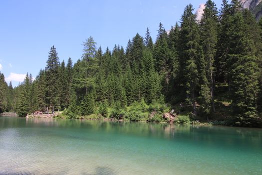 Braies Lake in Dolomites mountains forest trail in background, Sudtirol, Italy. Lake Braies is also known as Lago di Braies. The lake is surrounded by forest which are famous for scenic hiking trails.