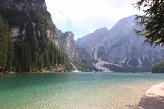 Braies Lake in Dolomites mountains forest trail in background, Sudtirol, Italy. Lake Braies is also known as Lago di Braies. The lake is surrounded by forest which are famous for scenic hiking trails.