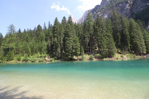 Braies Lake in Dolomites mountains forest trail in background, Sudtirol, Italy. Lake Braies is also known as Lago di Braies. The lake is surrounded by forest which are famous for scenic hiking trails.