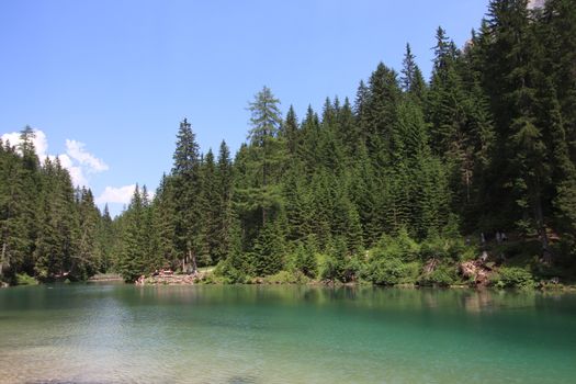 Braies Lake in Dolomites mountains forest trail in background, Sudtirol, Italy. Lake Braies is also known as Lago di Braies. The lake is surrounded by forest which are famous for scenic hiking trails.