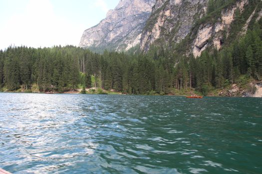 Braies Lake in Dolomites mountains forest trail in background, Sudtirol, Italy. Lake Braies is also known as Lago di Braies. The lake is surrounded by forest which are famous for scenic hiking trails.