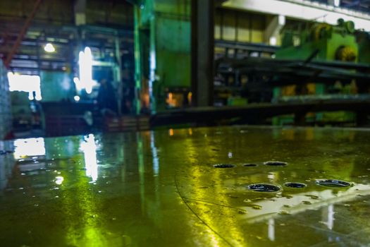 defocused abstract old factory background and oily horizontal steel surface in foreground.