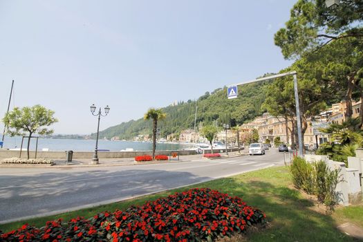 Scenic panoramic beltway road around lake Garda with medieval architecture buildings and rich northern Italy trees and plants growing on coast