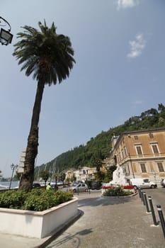 Amazing paved promenade with colorful mediterranean flowers. Luxury yachts, boats and sailing boats in the stunning harbor of Toscolano-Maderno, lake Garda, Lombardy region, Italy, Europe
