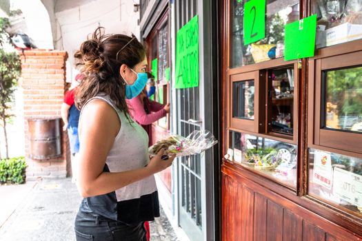 Alvaro Obregon, CDMX. Mexico. June 10, 2020. Woman buys cookies with surgical mask for the new normal. Covid 19