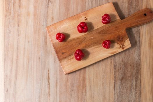 Apple and serrano peppers on chopping board on wooden surface. copy space