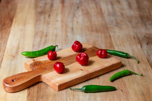 Apple and serrano peppers on chopping board on wooden surface. copy space