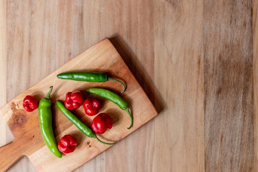 Apple and serrano peppers on chopping board on wooden surface. copy space