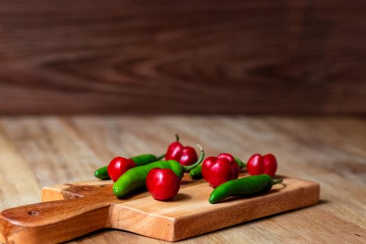 Apple and serrano peppers on chopping board on wooden surface. copy space