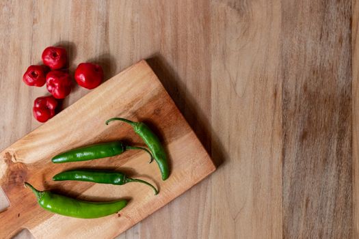 Apple and serrano peppers on chopping board on wooden surface. copy space