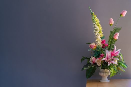 Fake flowers in a vase on wood table with gray background