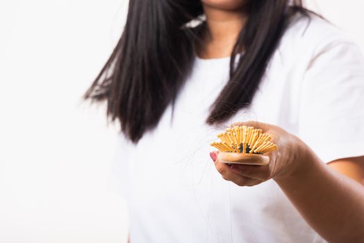 Asian woman unhappy weak hair she shows hairbrush with damaged long loss hair in the comb brush on hand, studio shot isolated on white background, medicine health care concept