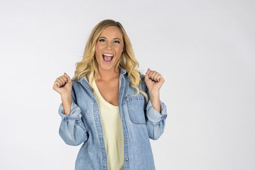A gorgeous blonde model pointing and showing emotion while posing in a studio environment