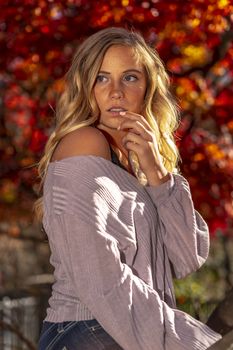 A gorgeous blonde model enjoys a Autumn day outdoors in a park