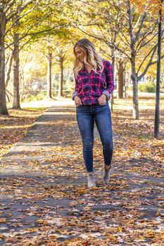 A gorgeous blonde model enjoys a Autumn day outdoors in a park