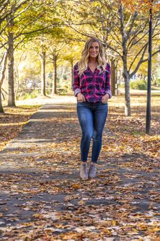 A gorgeous blonde model enjoys a Autumn day outdoors in a park