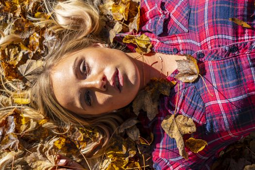 A gorgeous blonde model enjoys a Autumn day outdoors in a park