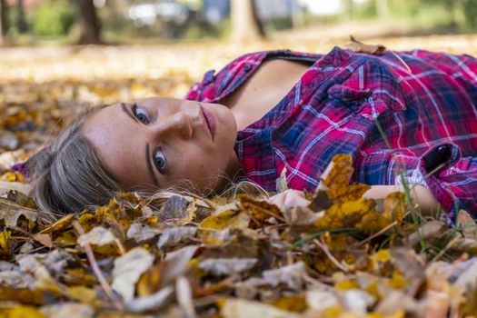 A gorgeous blonde model enjoys a Autumn day outdoors in a park