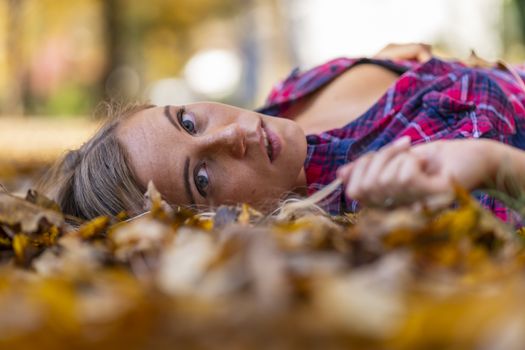 A gorgeous blonde model enjoys a Autumn day outdoors in a park