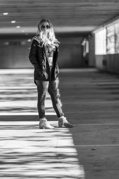 A gorgeous blonde model poses in a parking deck on an autumn day