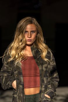A gorgeous blonde model poses in a parking deck on an autumn day