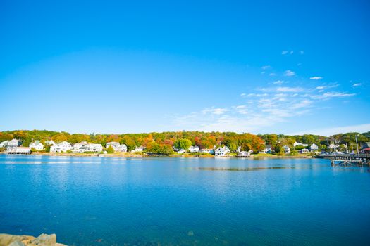 Fall colors and New england homes across harbor of Boothbay town and harbor, Maine USA.
