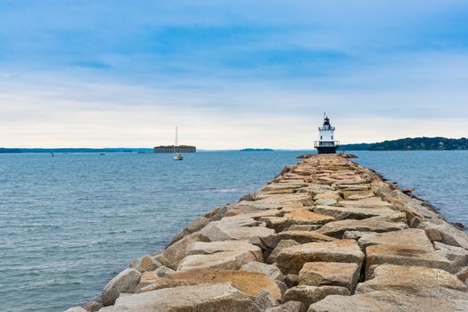 Portland Maine, Bug Lighthouse in bay with rock path and breawater leading to beacon.