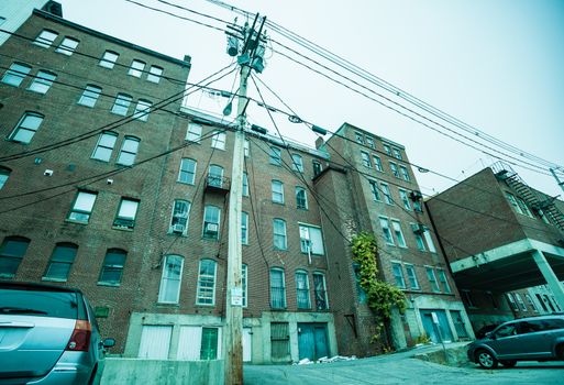 Brick medium level industrial building with power pole and lines typical of old American industry in vintage effect image..