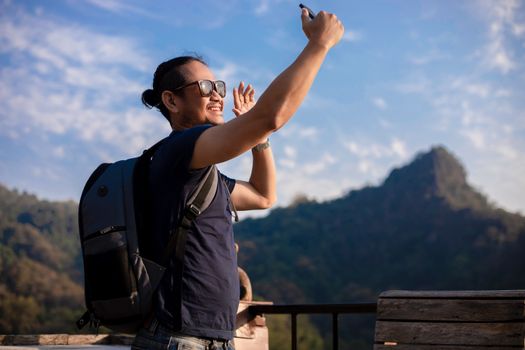 Asian man tourist is using a mobile phone to take a selfie for shared on social media, via social networking.