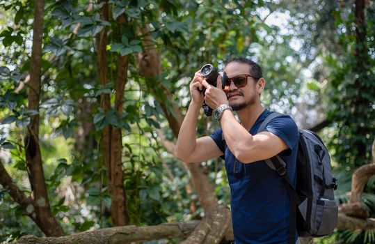 Asian men backpacks and traveler walking together and happy are taking photo on forest ,Relax time on holiday concept travel