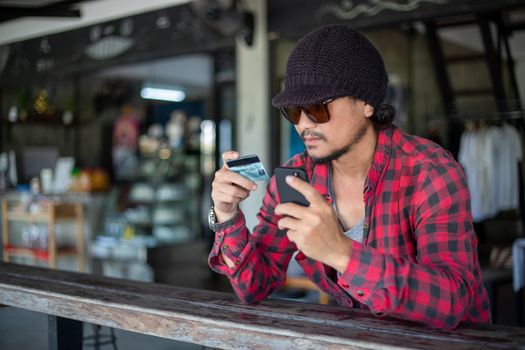Asian hipster man  are holding credit cards and using  mobile phones for online shopping.