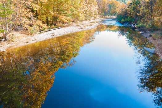 Sunday River converging reflections of golden fall color foliage in deep blue calm river water., Maine, USA.