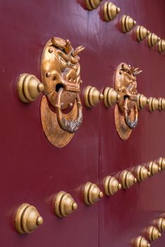 Golden colored chinese door knockers on a red gate