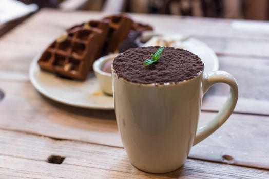 Cup of chocolate mocha with chocolate waffles on a wooden table