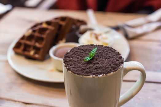 Cup of chocolate mocha with chocolate waffles on a wooden table