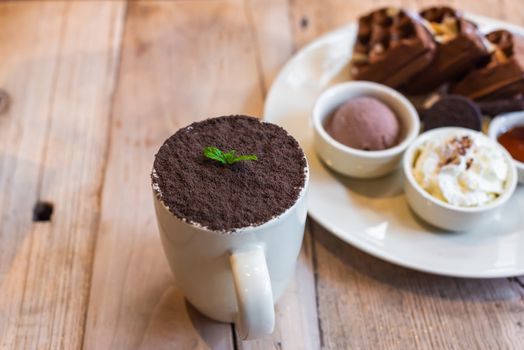 Chocolate mocha cup with dish of chocolate waffles on a wooden table