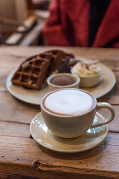 Cup of cappuccino with chocolate waffles on a wooden table