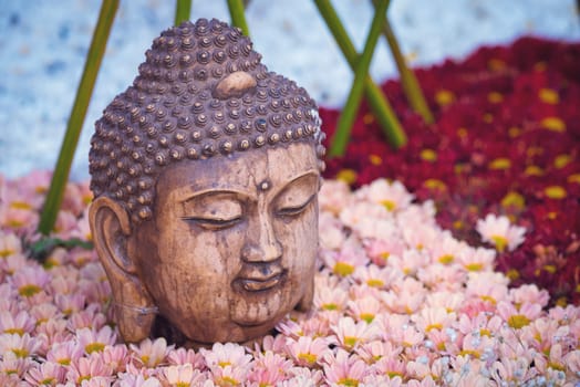 Buddha head statue on a flower bed in China