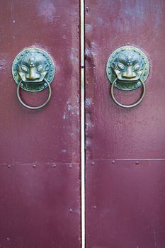 Golden colored chinese door knockers on a red gate