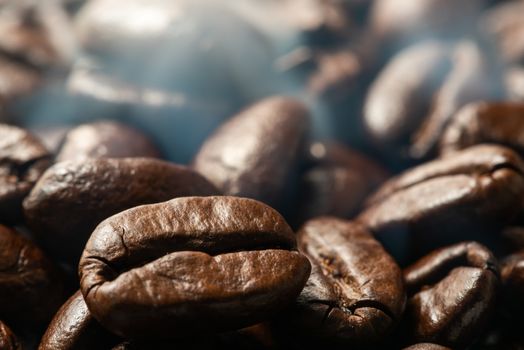 Heap of roasted coffee beans close-up view with smoke