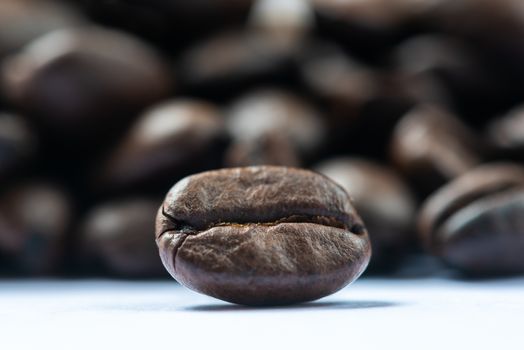 Roasted coffee bean with heap of beans in the background