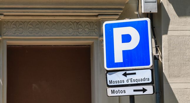 Blue parking sign that indicates in Catalan reserved for the police on the left and the motorbikes on the right