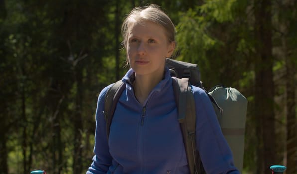 Close up portrait of young beautiful woman in the forest with backpack and trekking poles. Trekking in the forest, active and healthy lifestyle concept