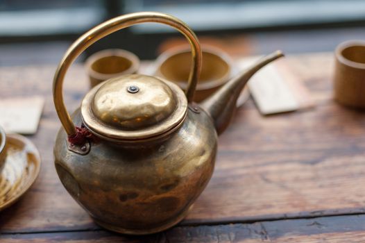 Copper teapot close up on a wooden table