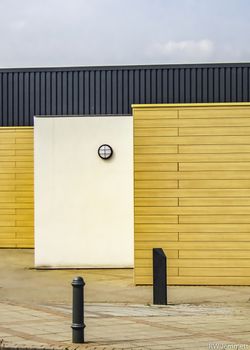 Modern architecture with yellow, black and white walls. Blue sky