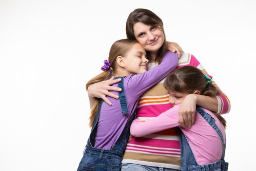 Children hug their beloved mom, mom happily looks in the frame
