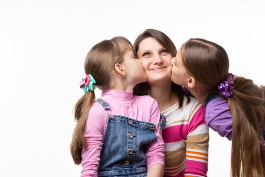 Two sisters kiss mom on the cheek, mom joyfully looks up