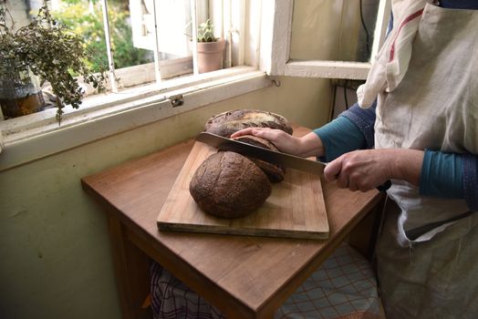 Cutting a loaf of bread into slices. Homemade bread. Healthy sour bread.