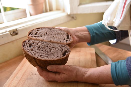 Cutting a loaf of bread into slices. Homemade bread. Healthy sour bread.